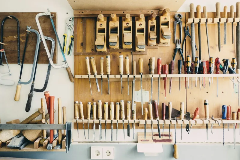 Hand planes, chisels, and other woodworking tools arranged on a wall; illustrative stock photograph.